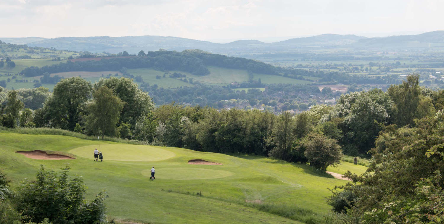 View over green at Broadway Golf Club, with views of countryside in the background